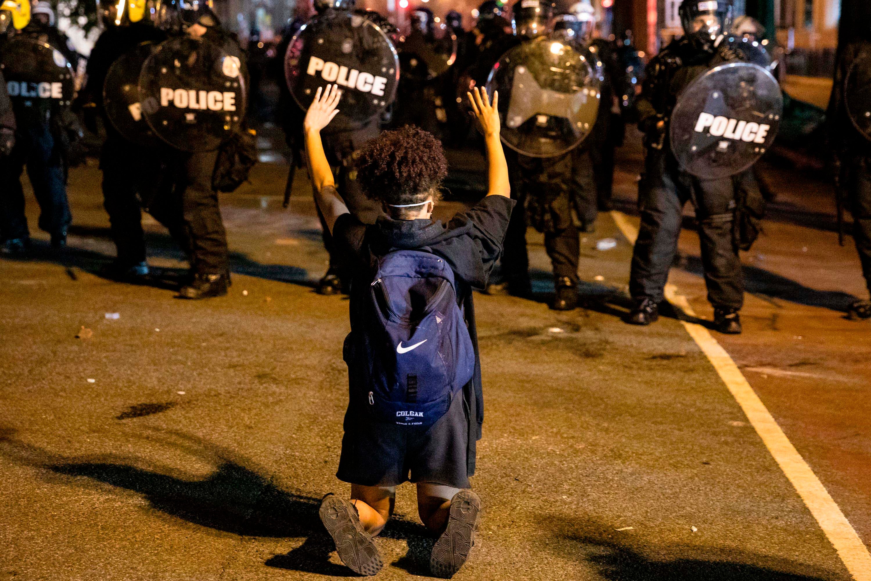 A demonstrator kneels facing a police line in front of the White House while protesting the police killing of George Floyd. Washington, DC, May 31, 2020. 