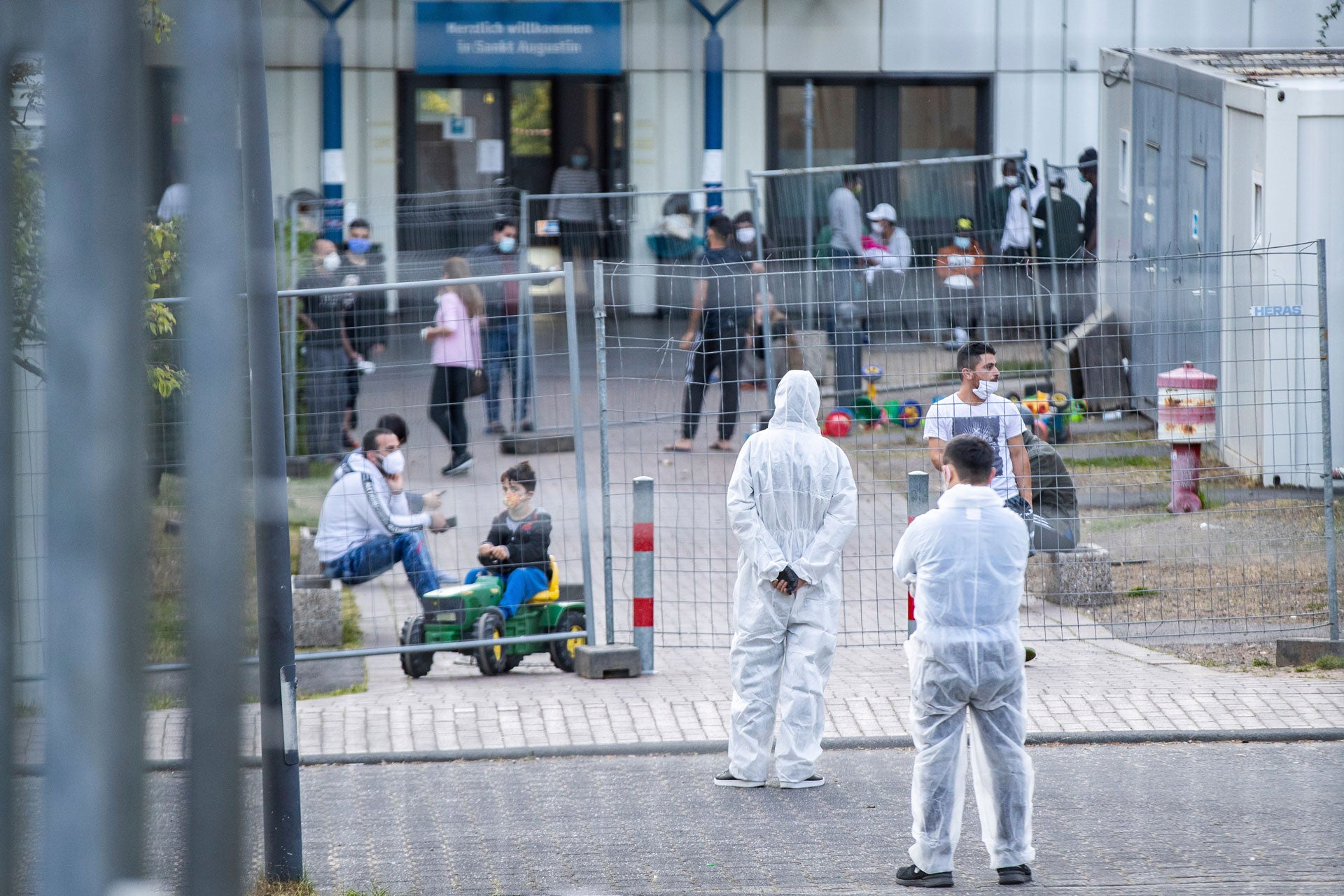 Members of a security service stand in protective gear inside a reception center for asylum seekers in North Rhine-Westphalia where 70 people tested positive for the virus that causes Covid-19, May 17, 2020. 
