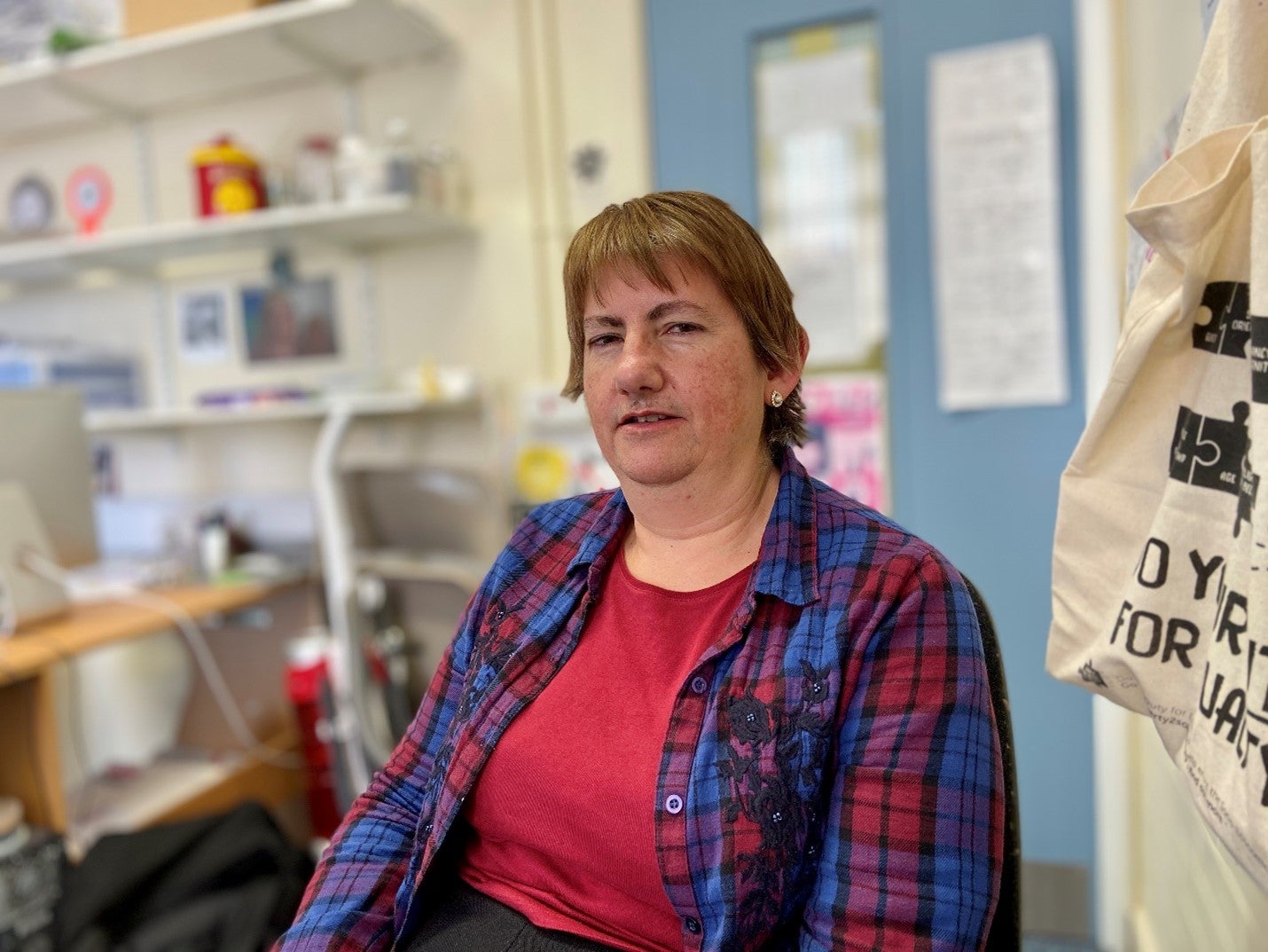 A woman blue and red plaid shirt poses for the camera