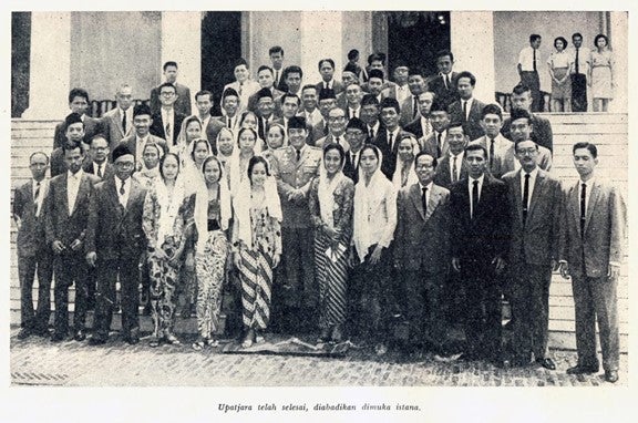 A large group of people poses for a photo on the steps of a building