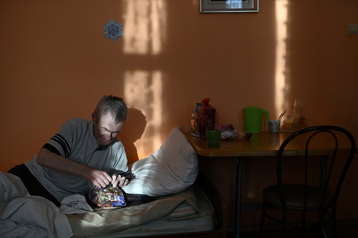 A resident of a nursing home opens a bag with sweets.