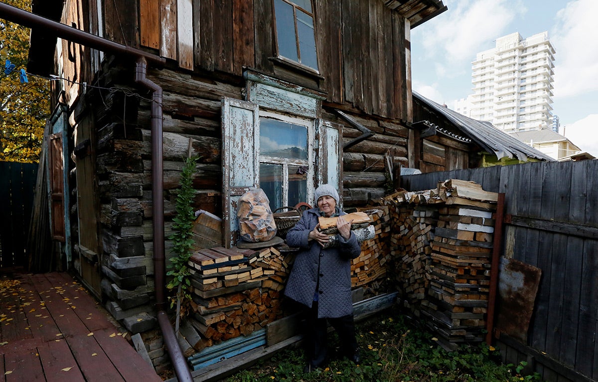 A pensioner carries logs in the courtyard of her wooden house where she opened a private museum of the old quarter.