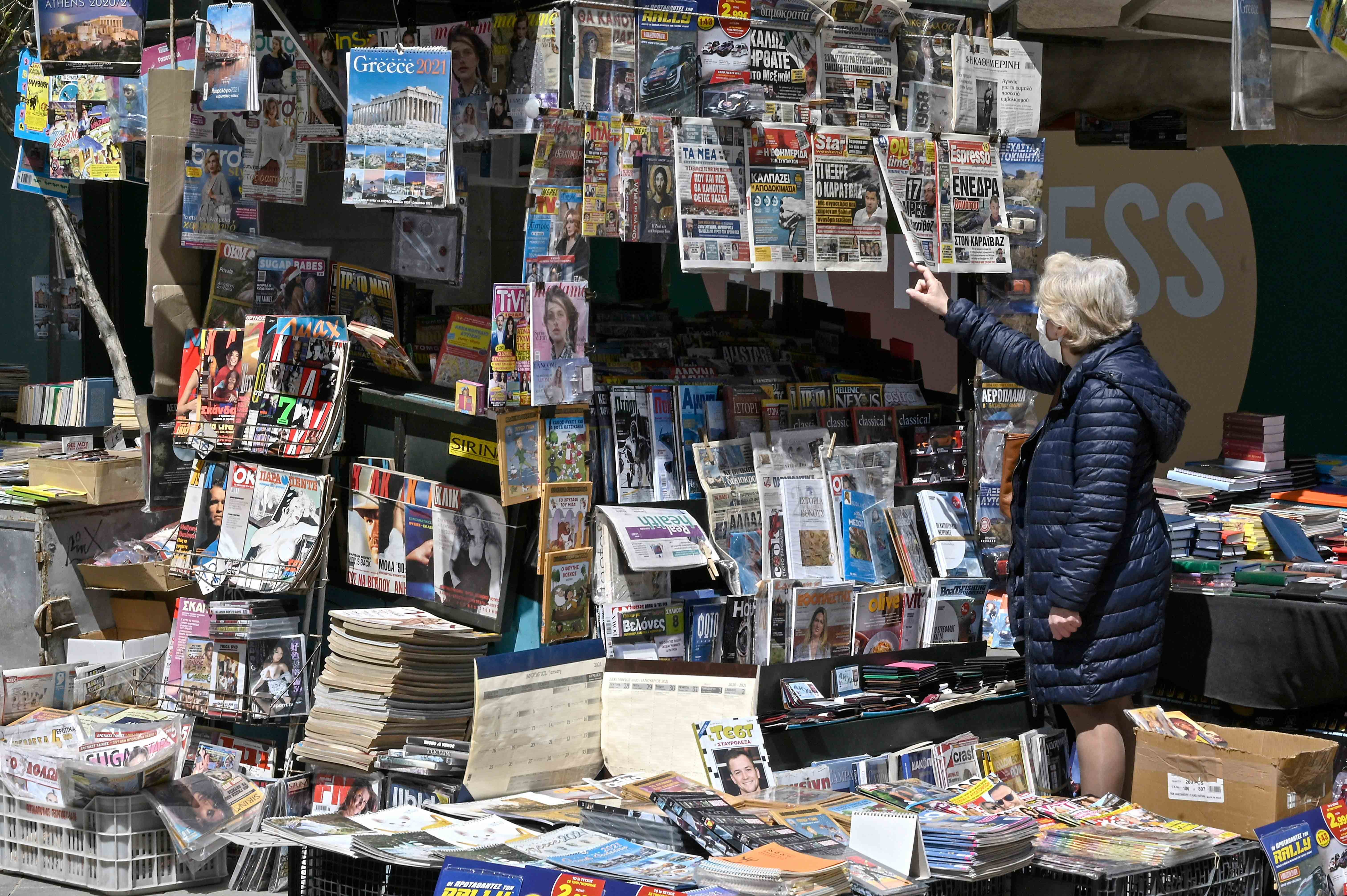 A woman reads newspaper's headlines referring to the killing of a Greek journalist in Athens on April 10, 2021.