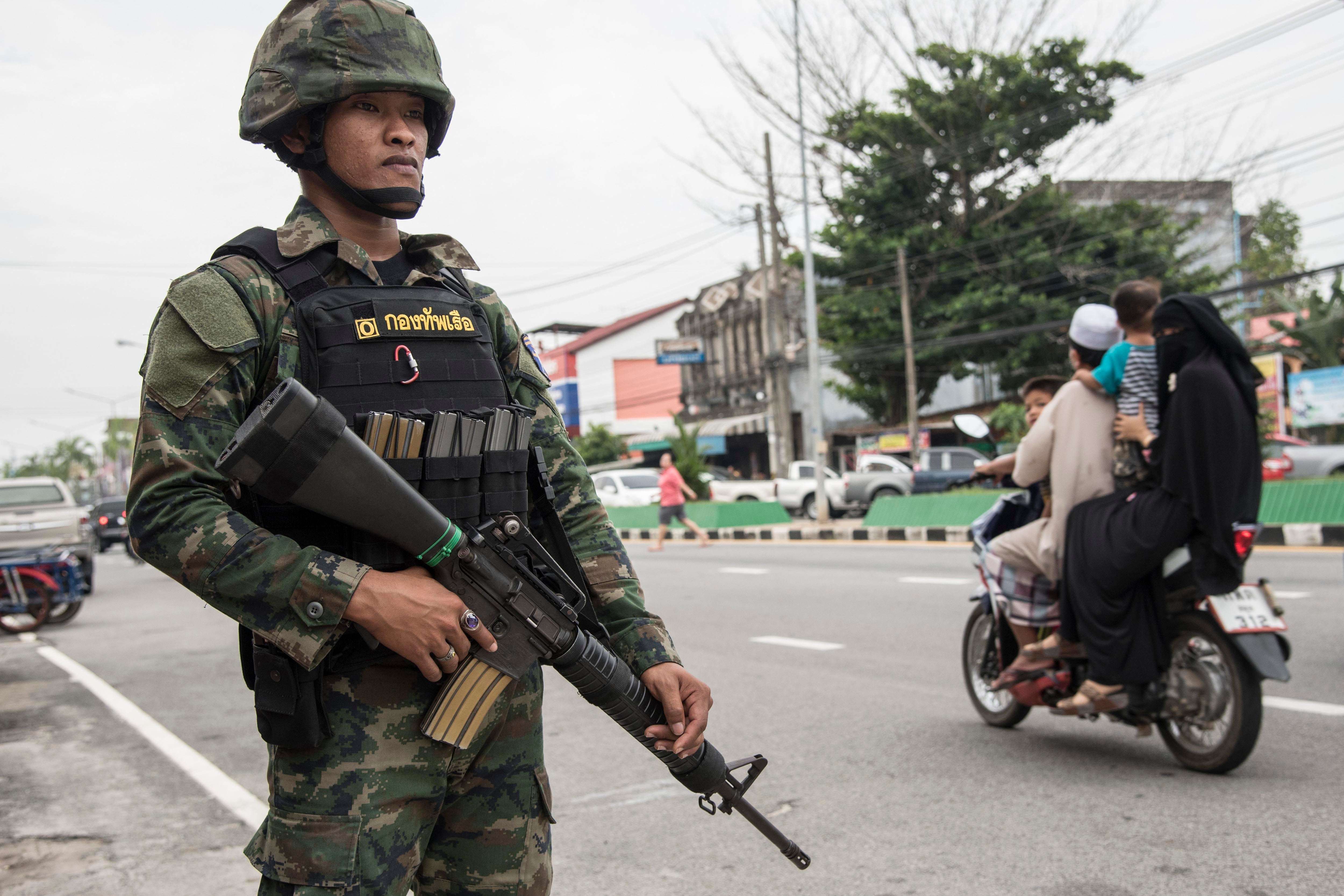 A uniformed police officer holding a gun next to a street