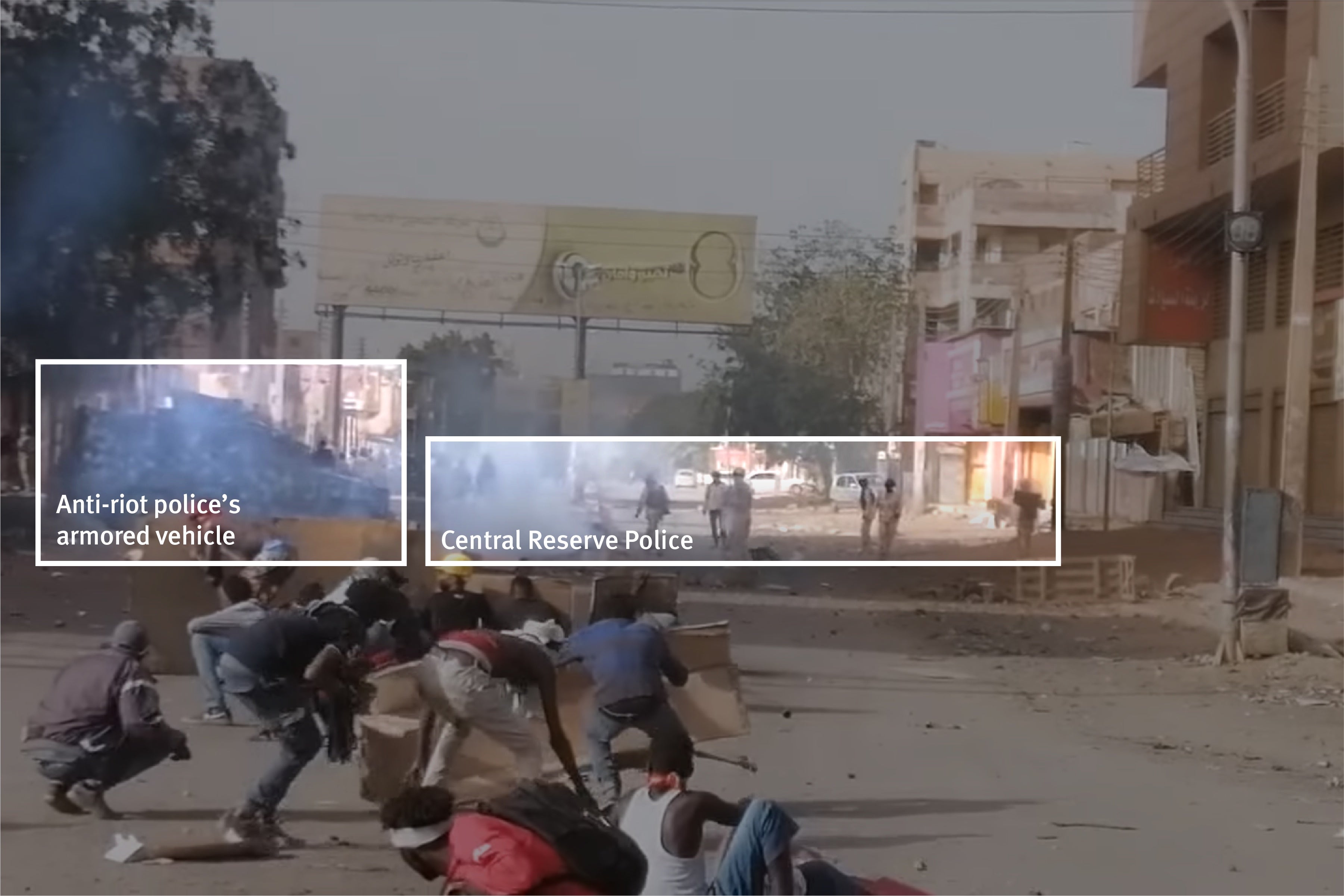 A screenshot from the video posted on Facebook. In the foreground protesters are using cardboard sheets as shields. In the background, a four-wheel armored vehicle is on the left with approximately 10 CRP officers in khaki camouflage standing nearby.