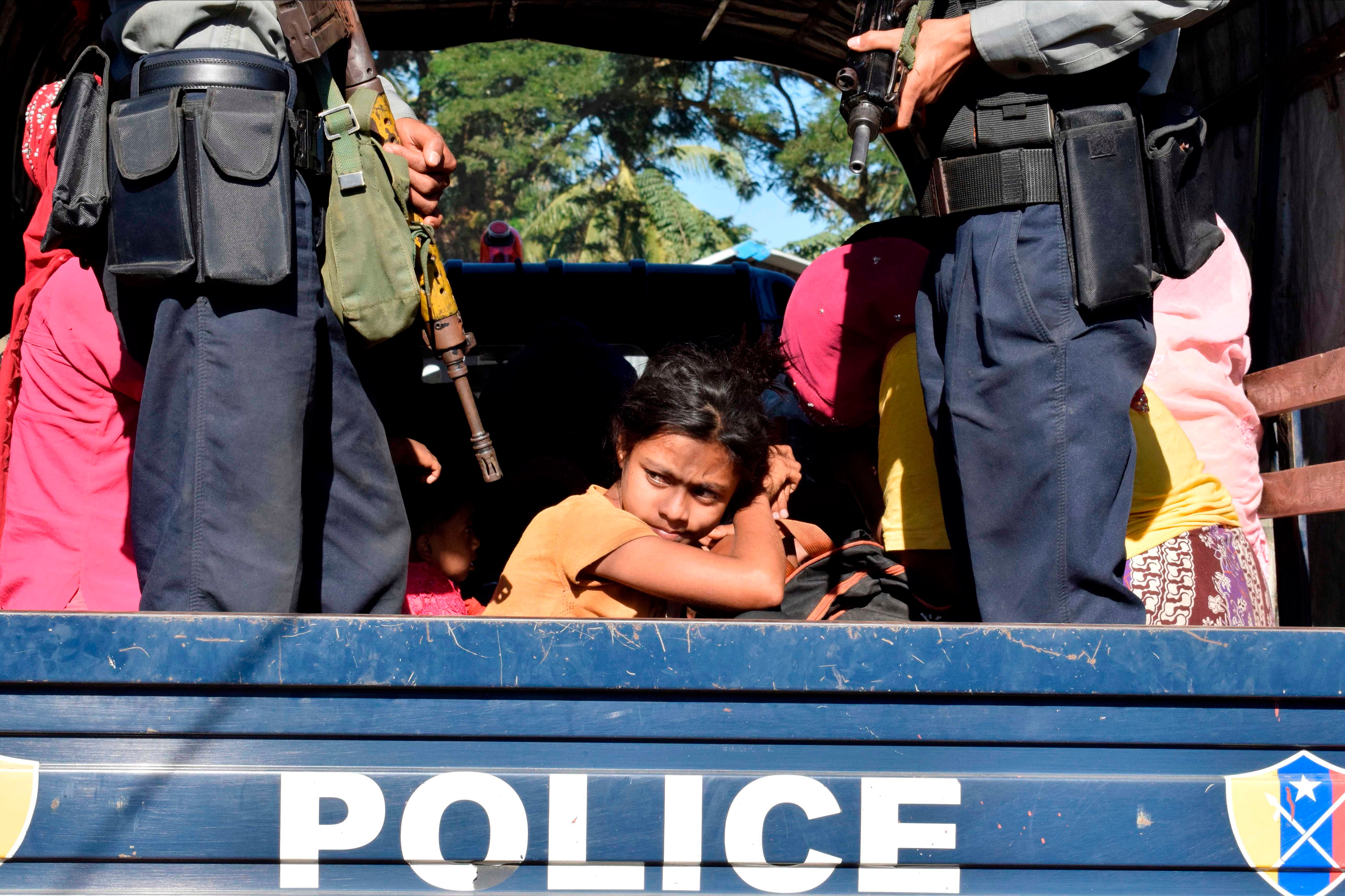 A person looks out from the back of a police truck
