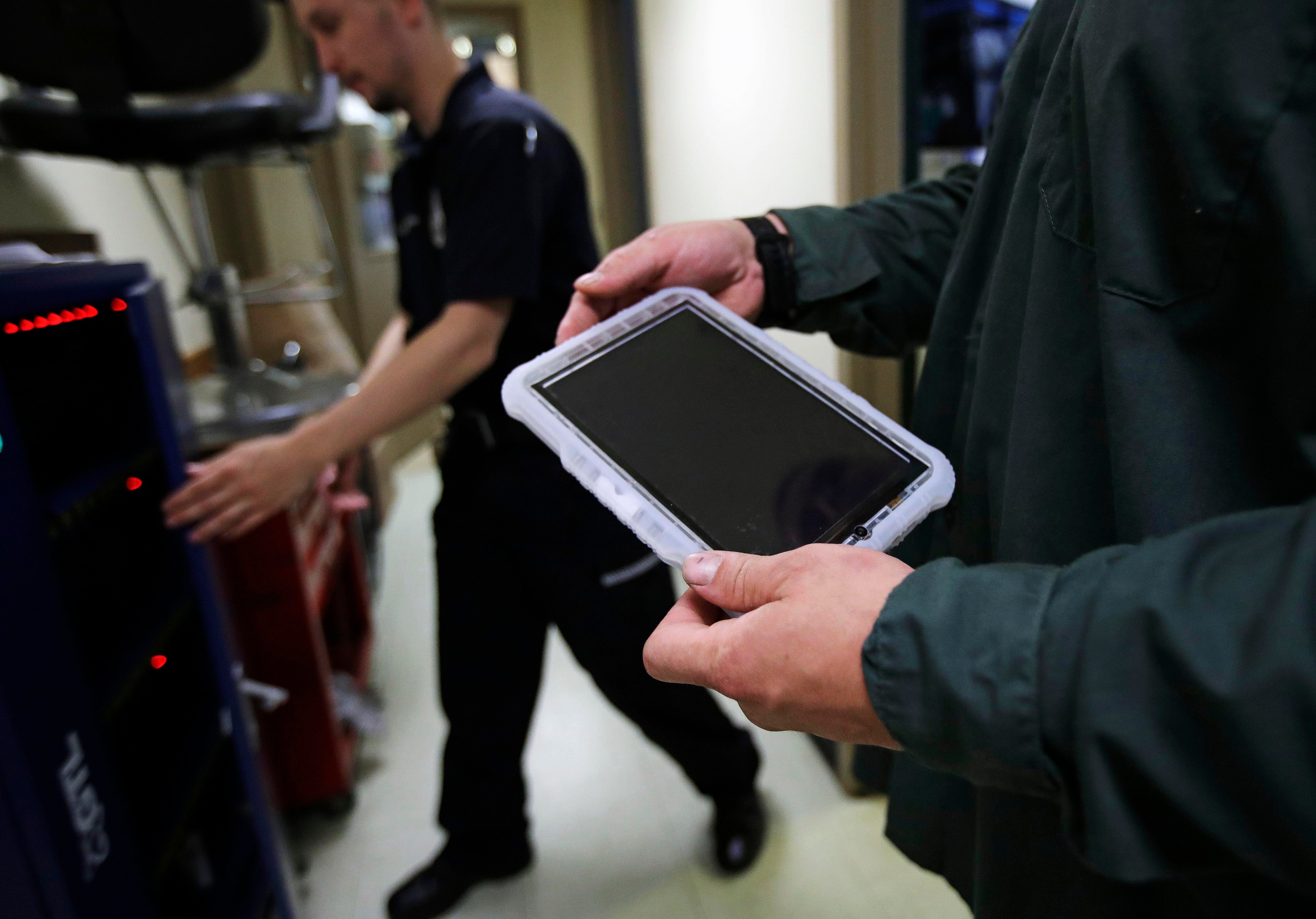 A prisoner holds a tablet that he checked out from a corrections officer, left, at the New Hampshire State Prison for Men, in Concord, N.H., July 23, 2018. © 2018 Charles Krupa/AP Photo