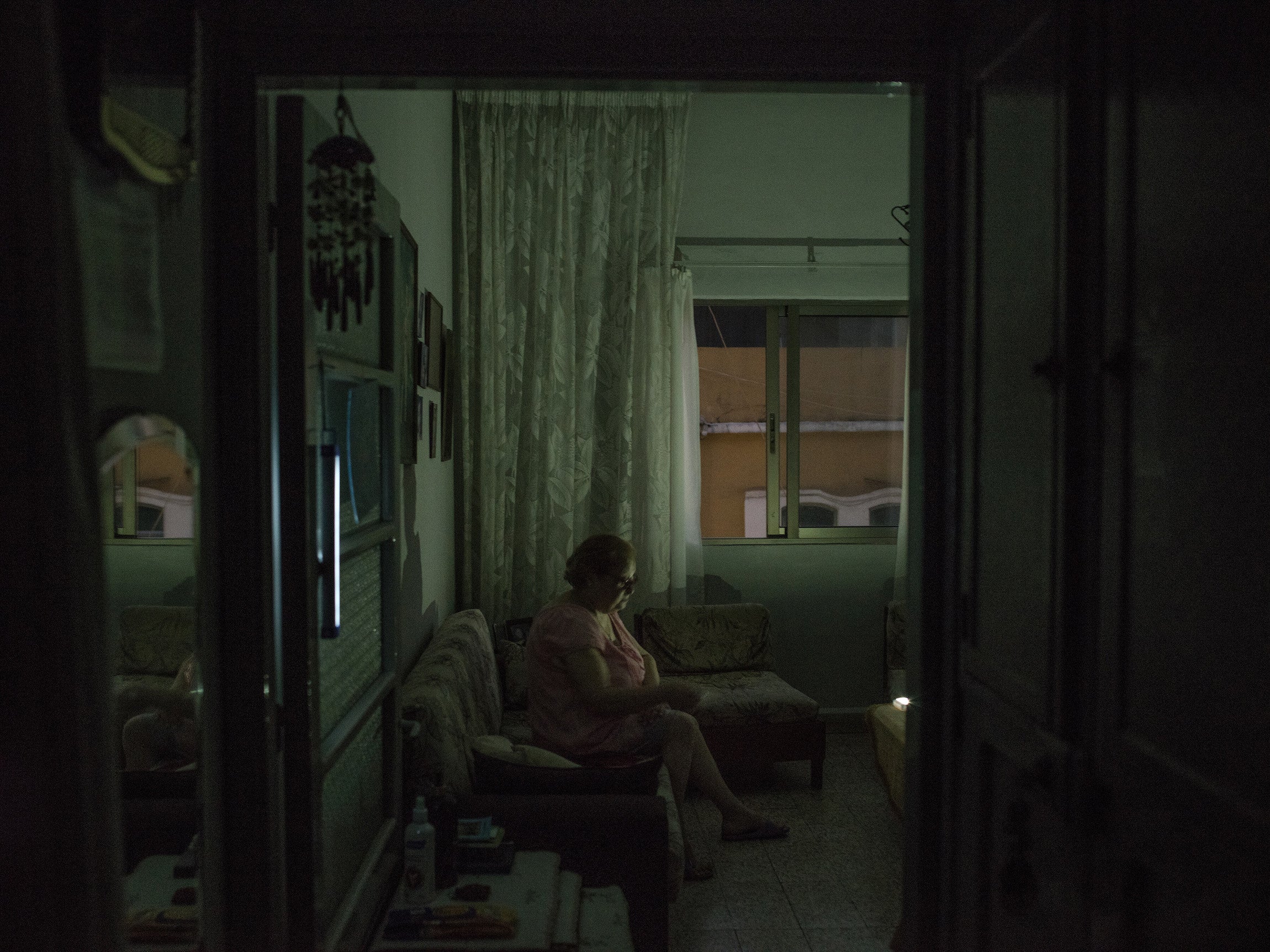 A woman uses chargeable lights in her living room during power cuts