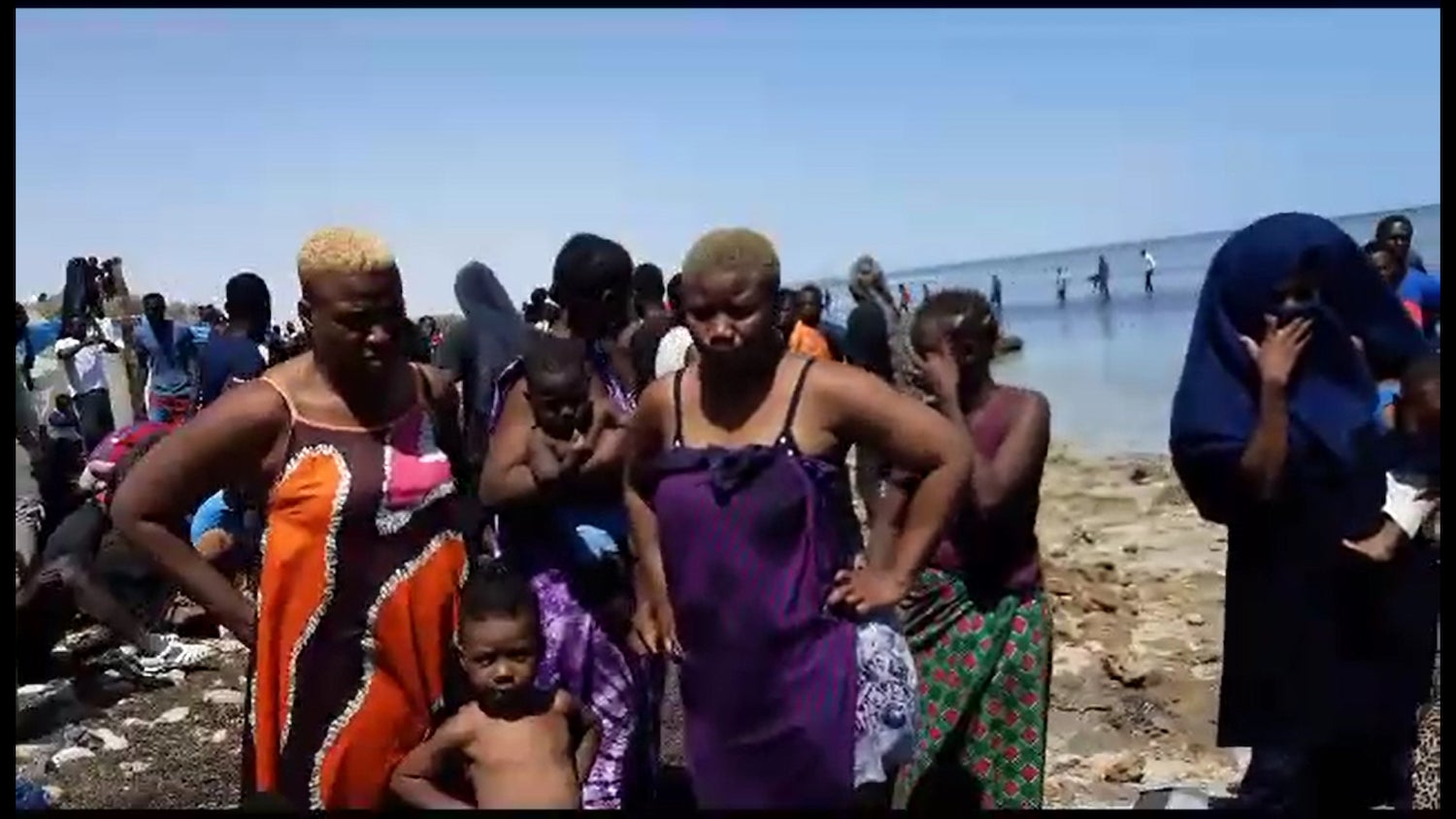 Women and children expelled by Tunisian authorities to the Libyan border stand by the shore, July 6, 2023. 