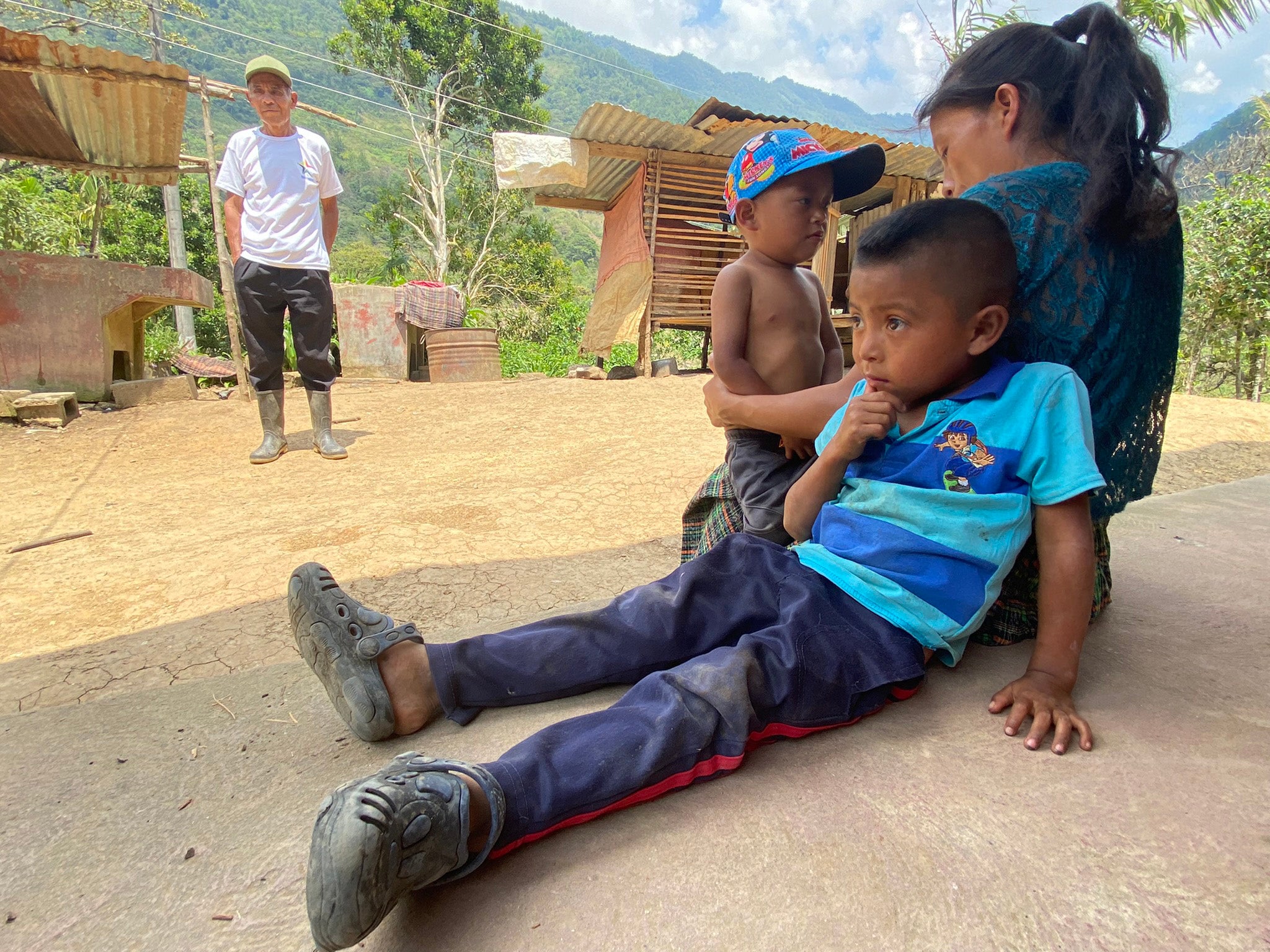 Father-in-law, daughter-in-law, and her two sons, outside their home in Quejá