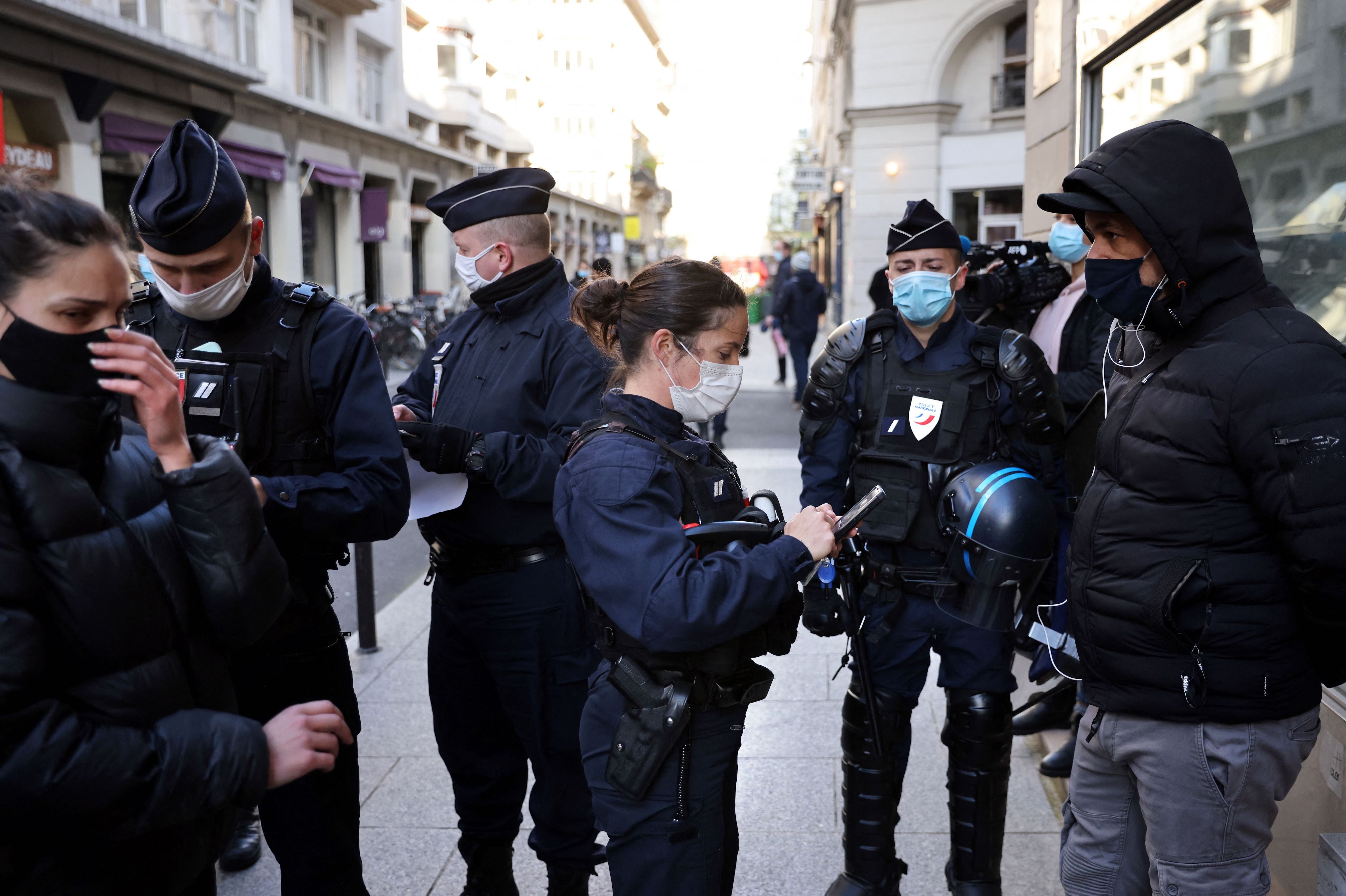 Police officers check IDs of demonstrators near the Palais Vivienne event venue in Paris, France, April 6, 2021.