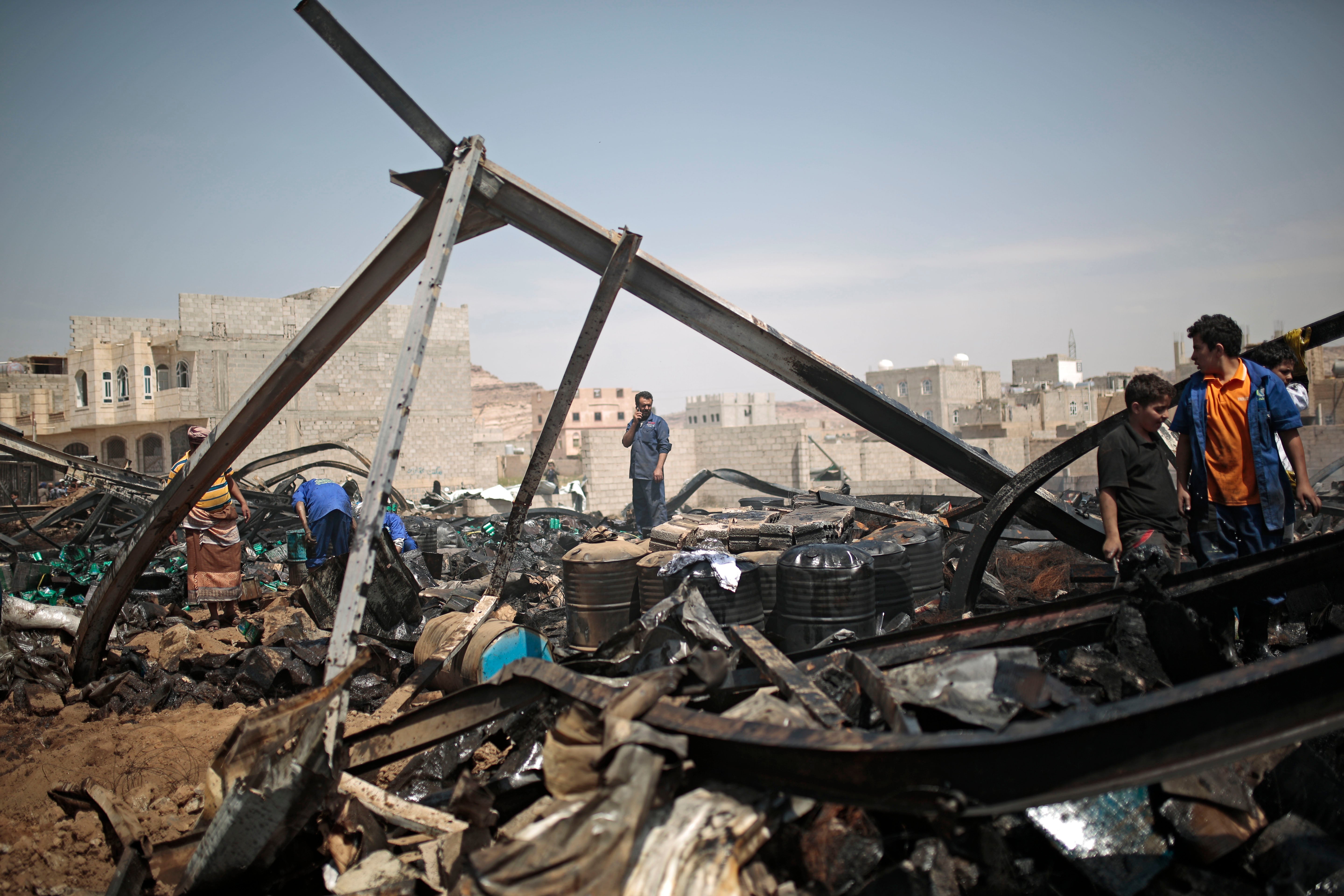 Workers salvage oil canisters from the wreckage of a store hit by Saudi-led airstrikes in Sanaa, Yemen, July 2, 2020.