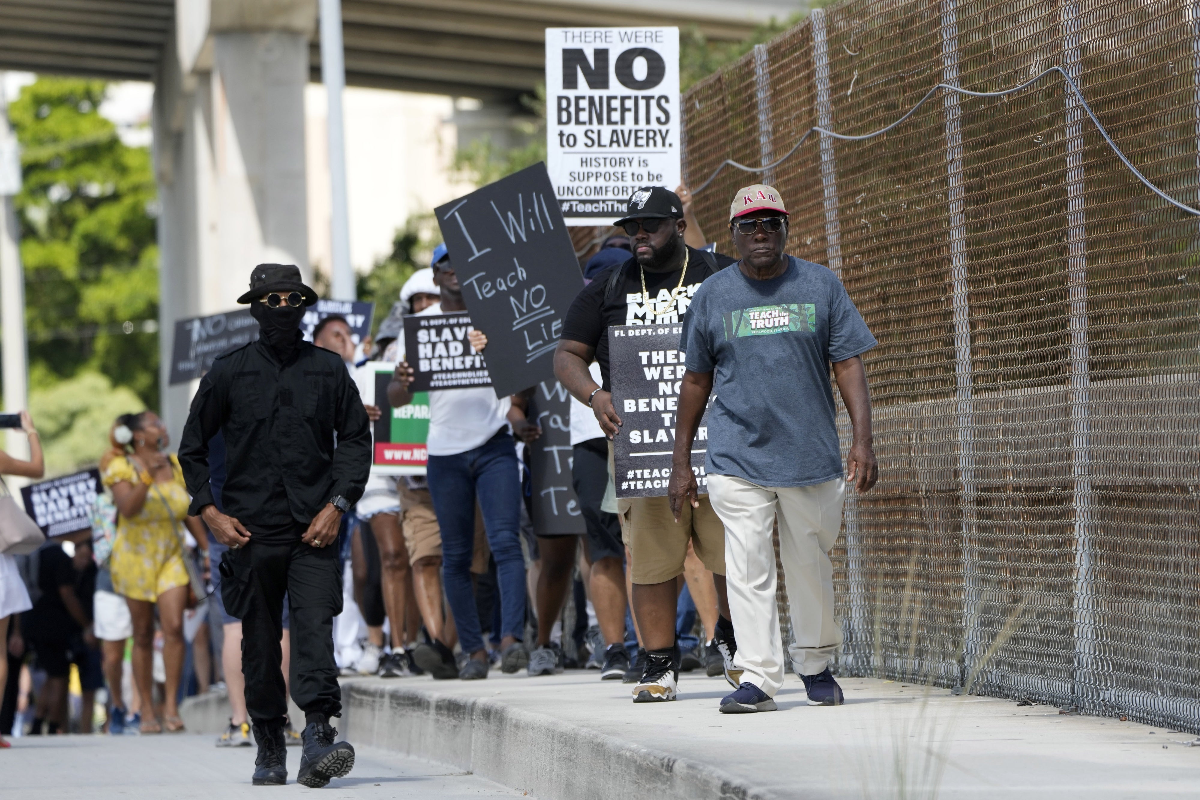 A group marches holding up protest signs