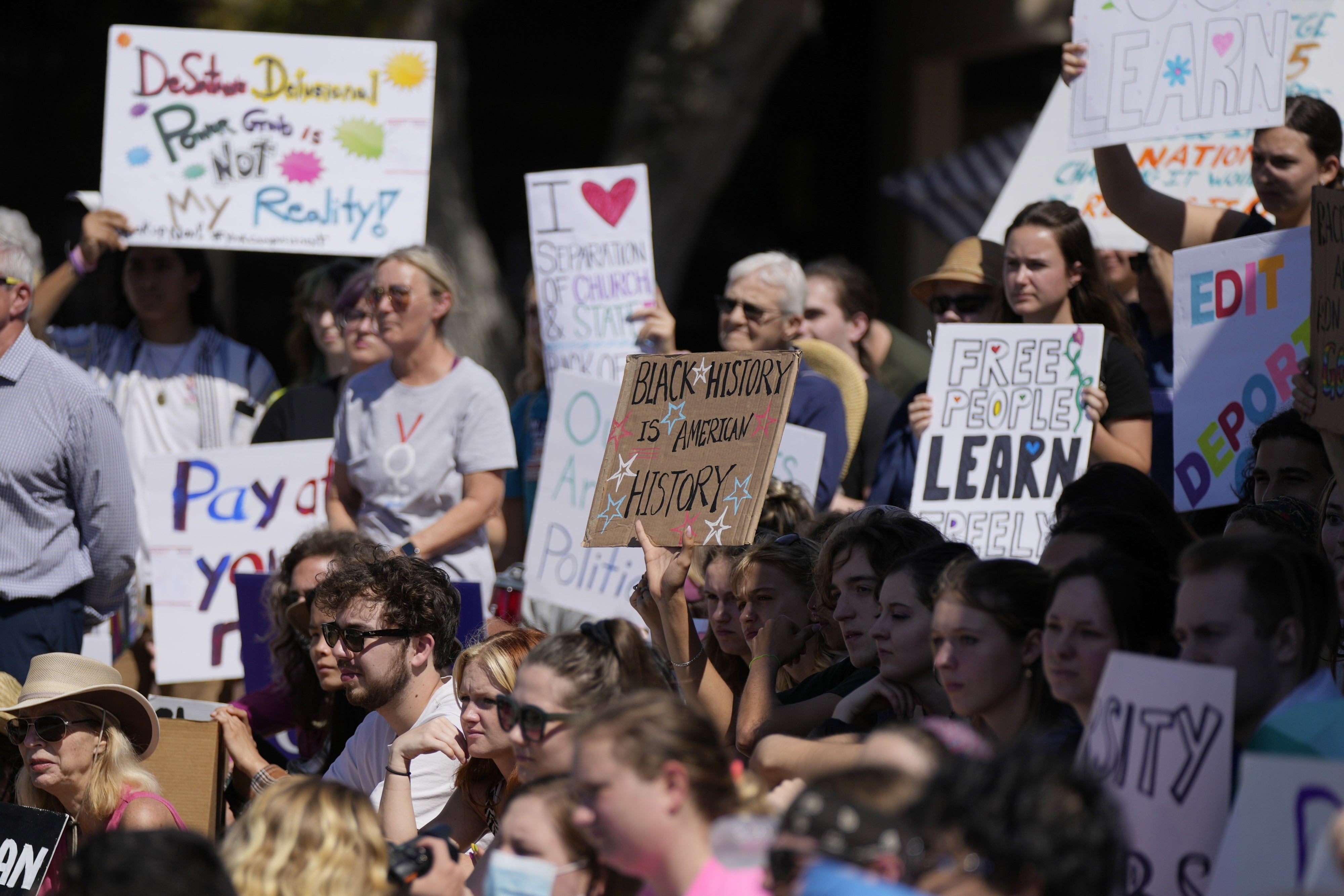 Protesters hold up placards including a sign that reads "Black history is American history"