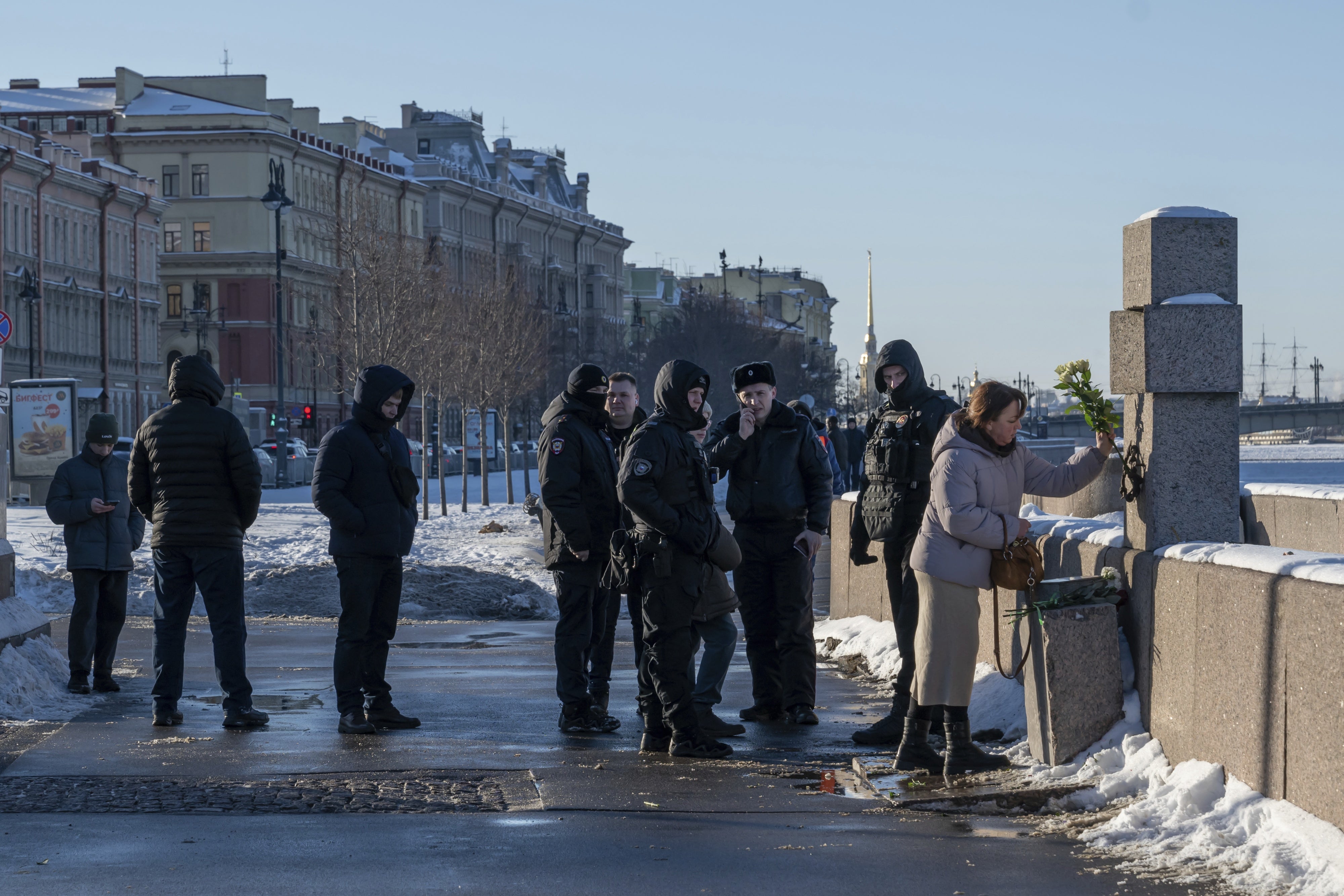 Sous le regard de policiers russes, une femme déposait des fleurs sur le site d’une structure dénommée « Mémorial des victimes de la répression politique » à Saint-Pétersbourg, le 16 février 2025. 