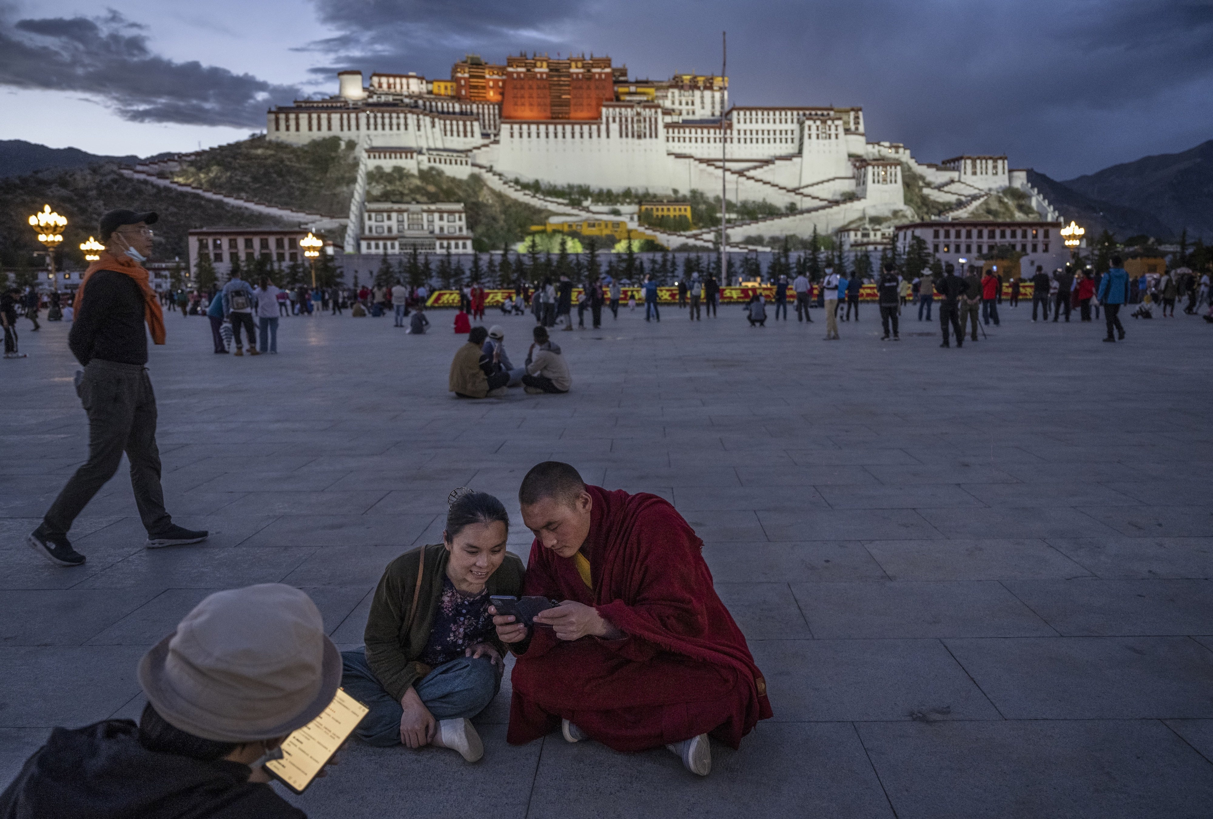 A Tibetan Buddhist monk and a woman share a mobile phone outside the Potala Palace in Lhasa, Tibet Autonomous Region, China, on June 1, 2021. 