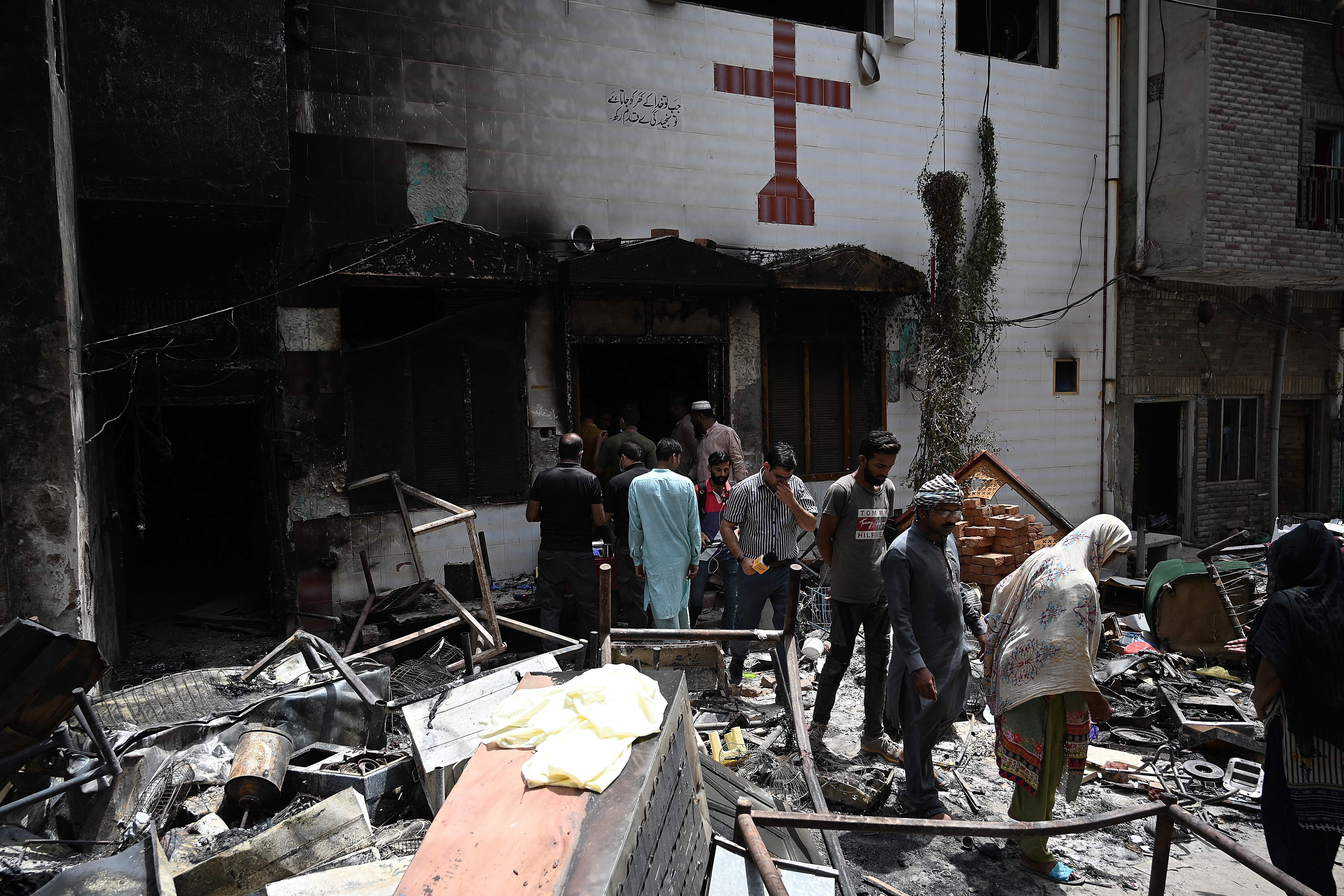 Police and residents stand amid debris outside the torched St. John Church
