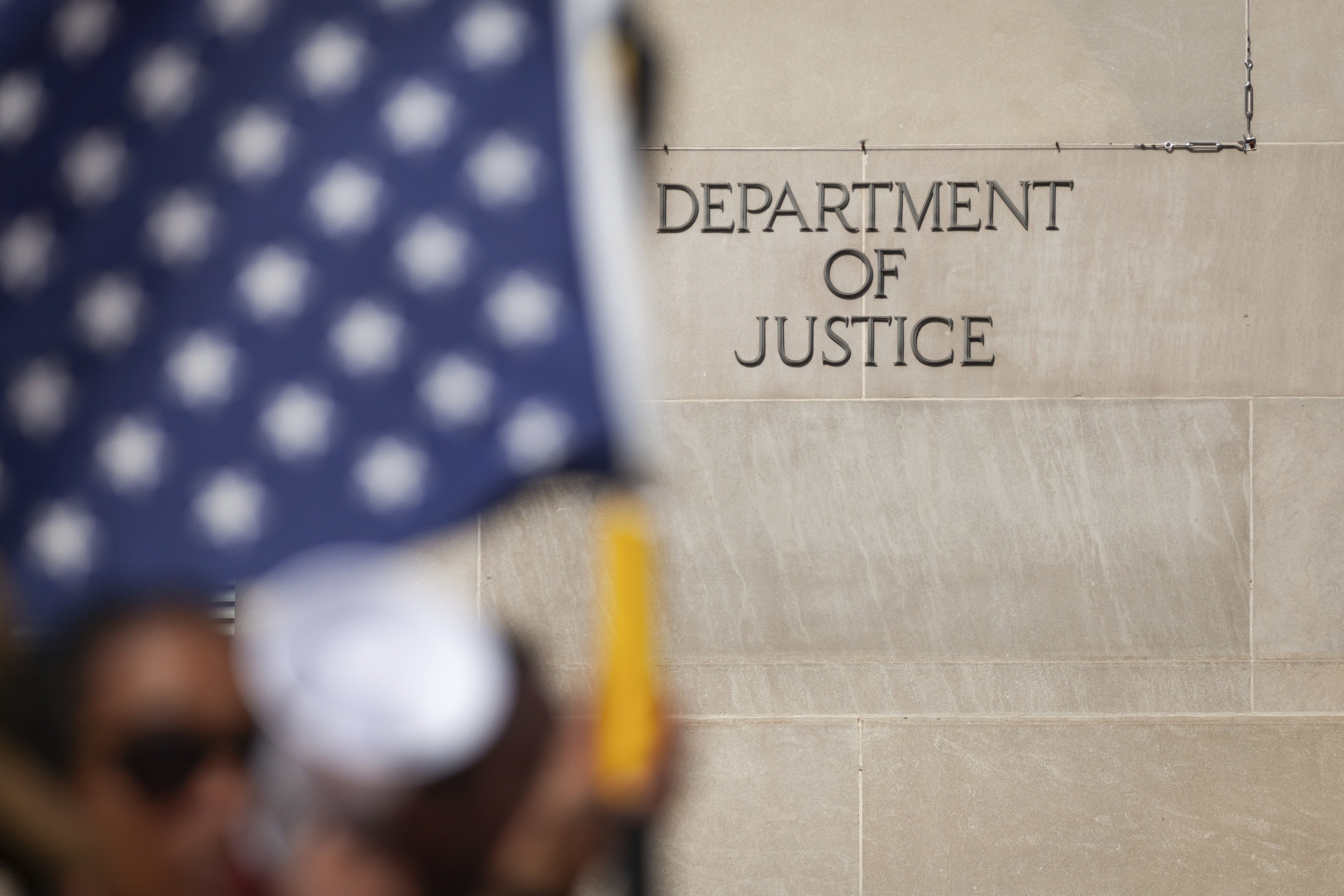 People pass the Department of Justice during a march against Trump administration policies in Washington, DC, March 4, 2025. 