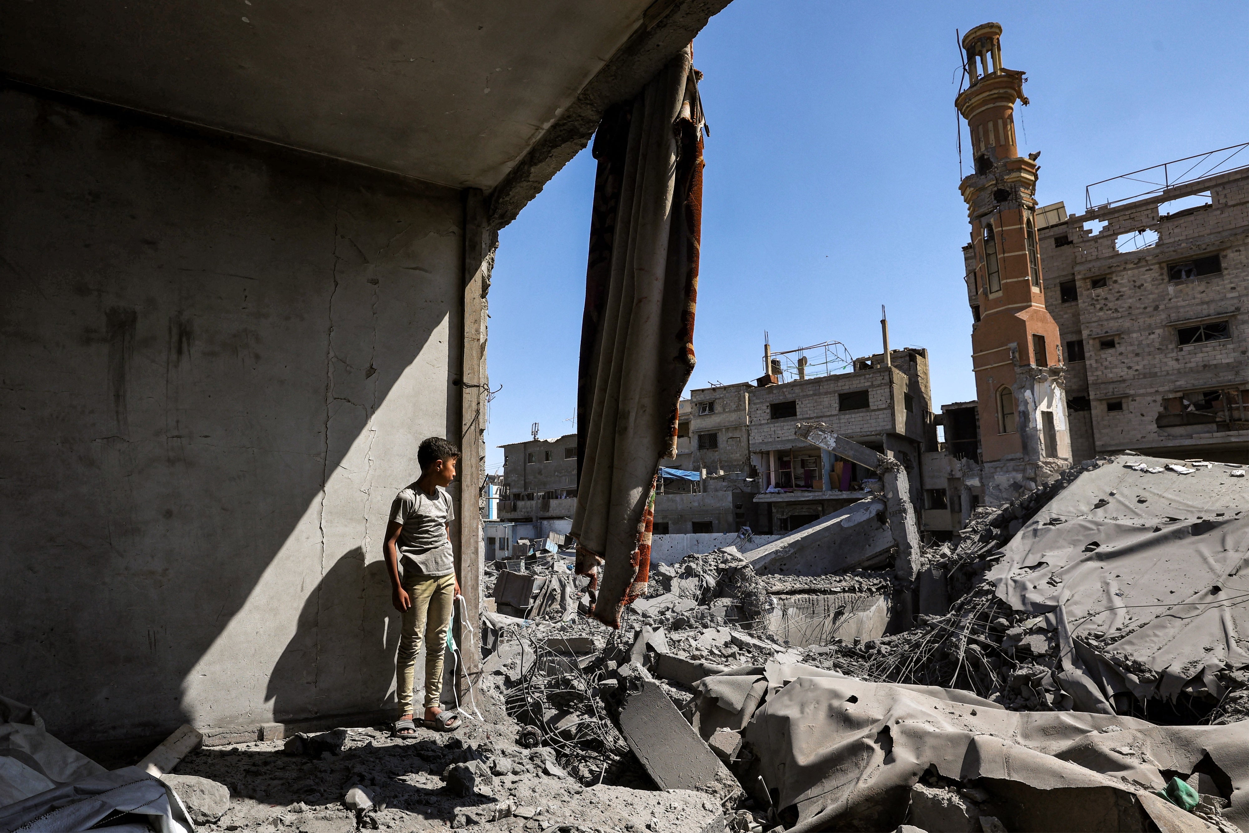 A boy stands amid the ruins of a collapsed building following Israeli bombardment in the Bureij camp for Palestinian refugees in the central Gaza Strip, May 23, 2025.
