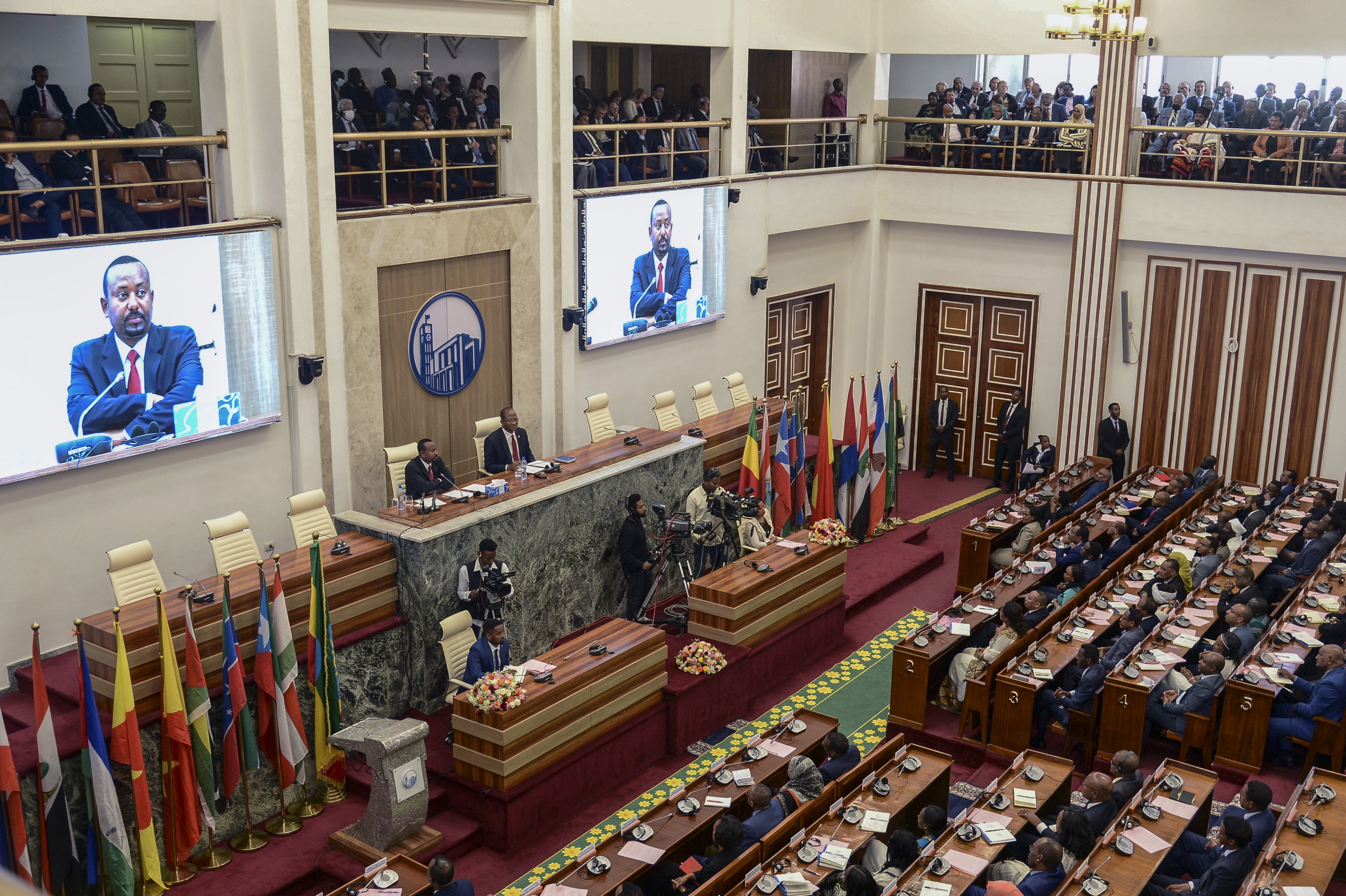 Ethiopia's Prime Minister Abiy Ahmed, center-left on the podium and on the video screens, addresses the parliament in Addis Ababa
