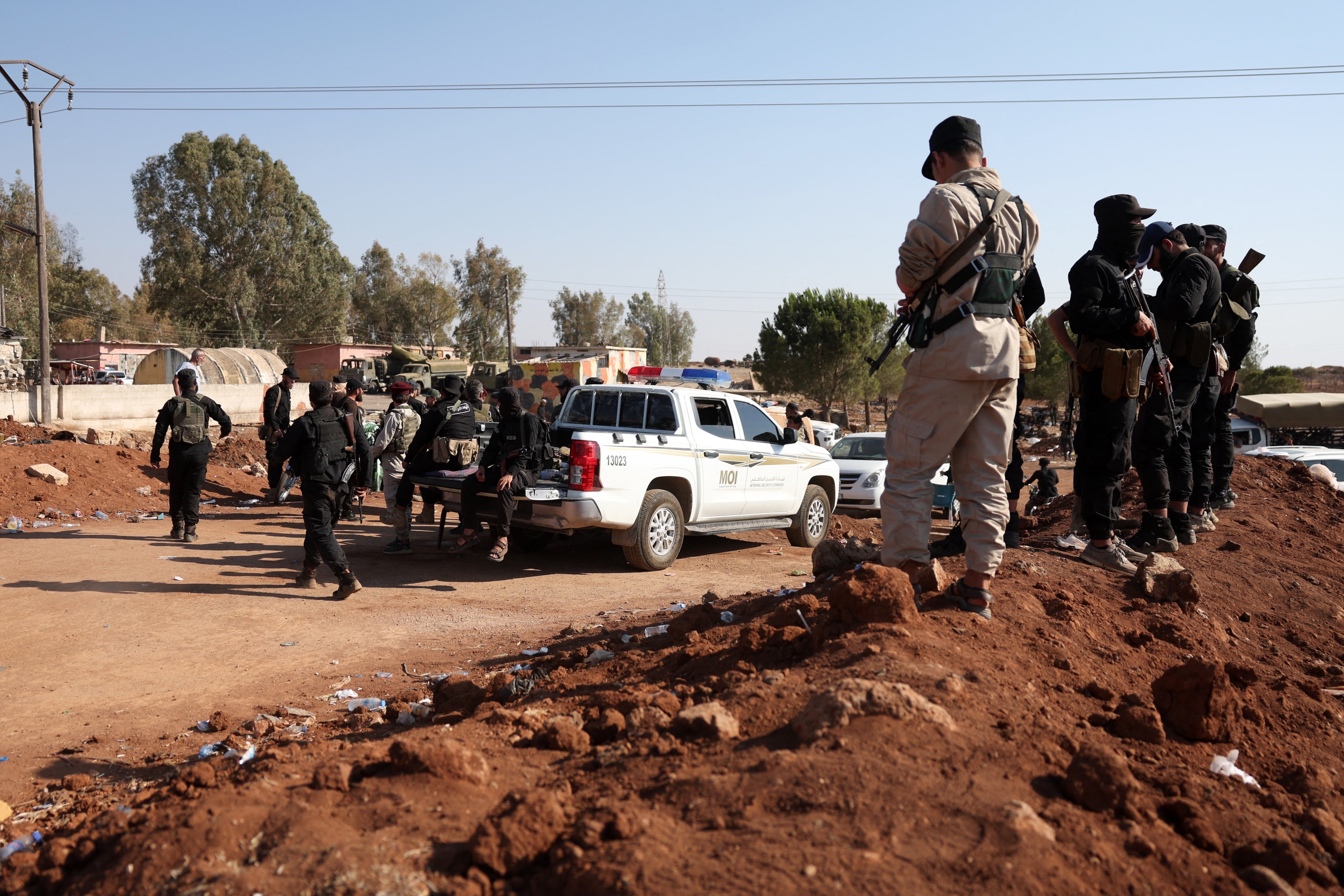 Syrian government security forces stand atop an earth barrier that they created as a buffer during their deployment in Busra al-Harir in Syria’s southern Daraa province on July 21, 2025.