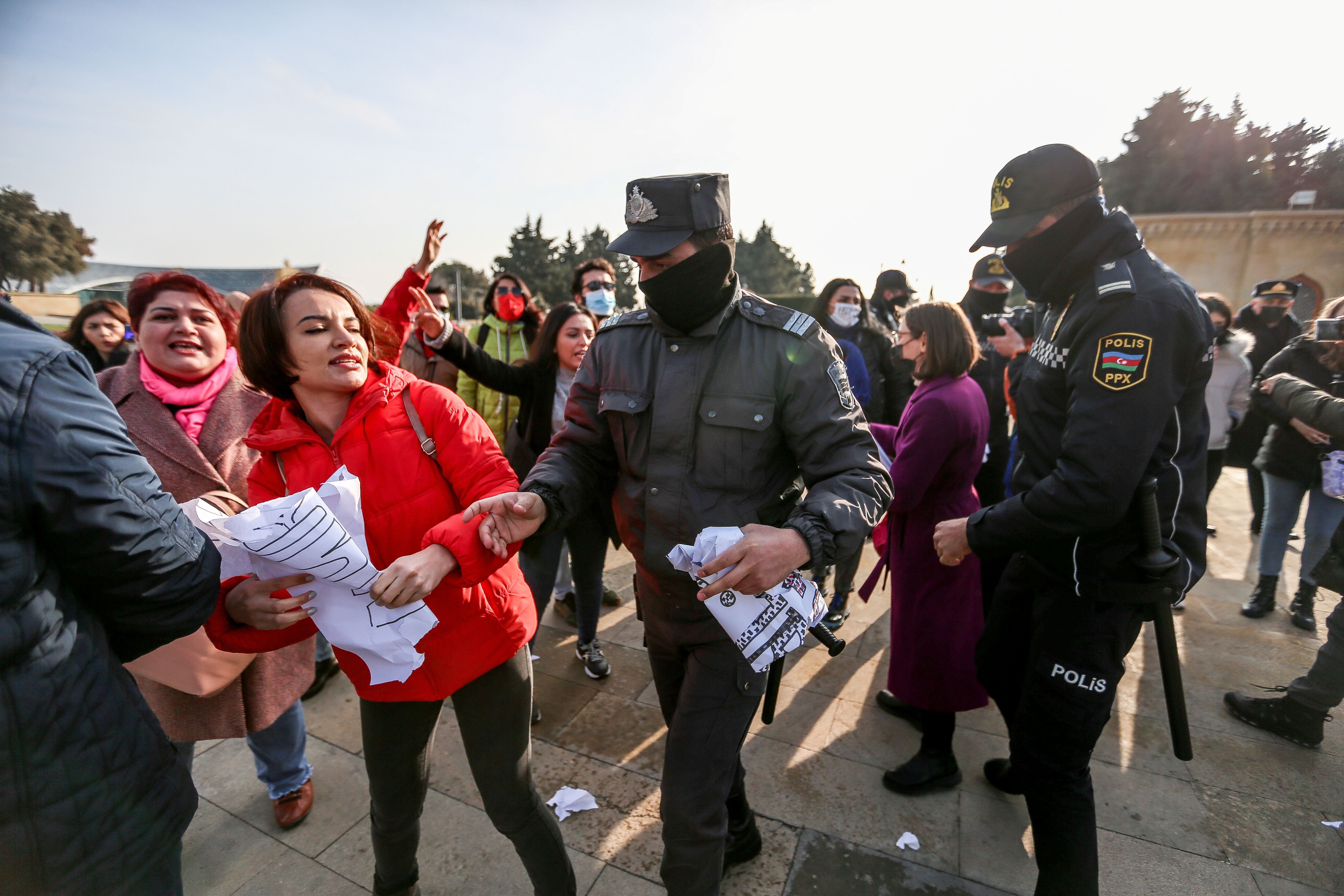 A woman holding a protest sign is surrounded by police