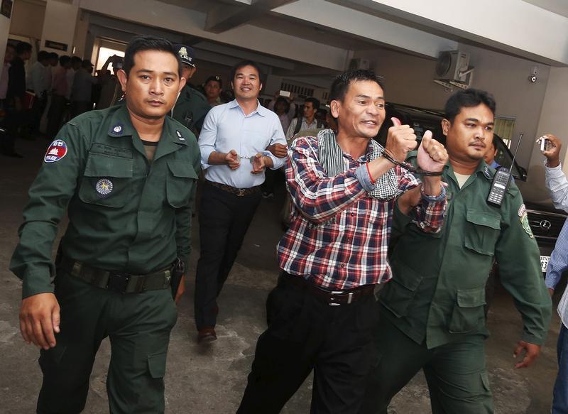 Supporters of the Cambodia National Rescue Party (CNRP) are escorted by Cambodian police officers at the Phnom Penh Municipal Court on July 21, 2015.