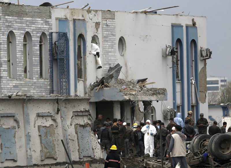 A forensic expert inspects through a window of a government security building after a blast in Kabul, Afganistan, April 19, 2016.