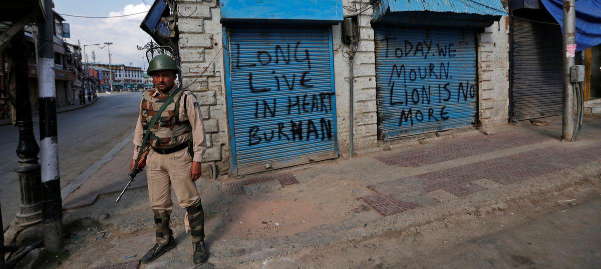 An Indian policeman stands guard in front of the closed shops painted with graffiti during a curfew in Srinagar July 12, 2016. REUTERS/Danish Ismail