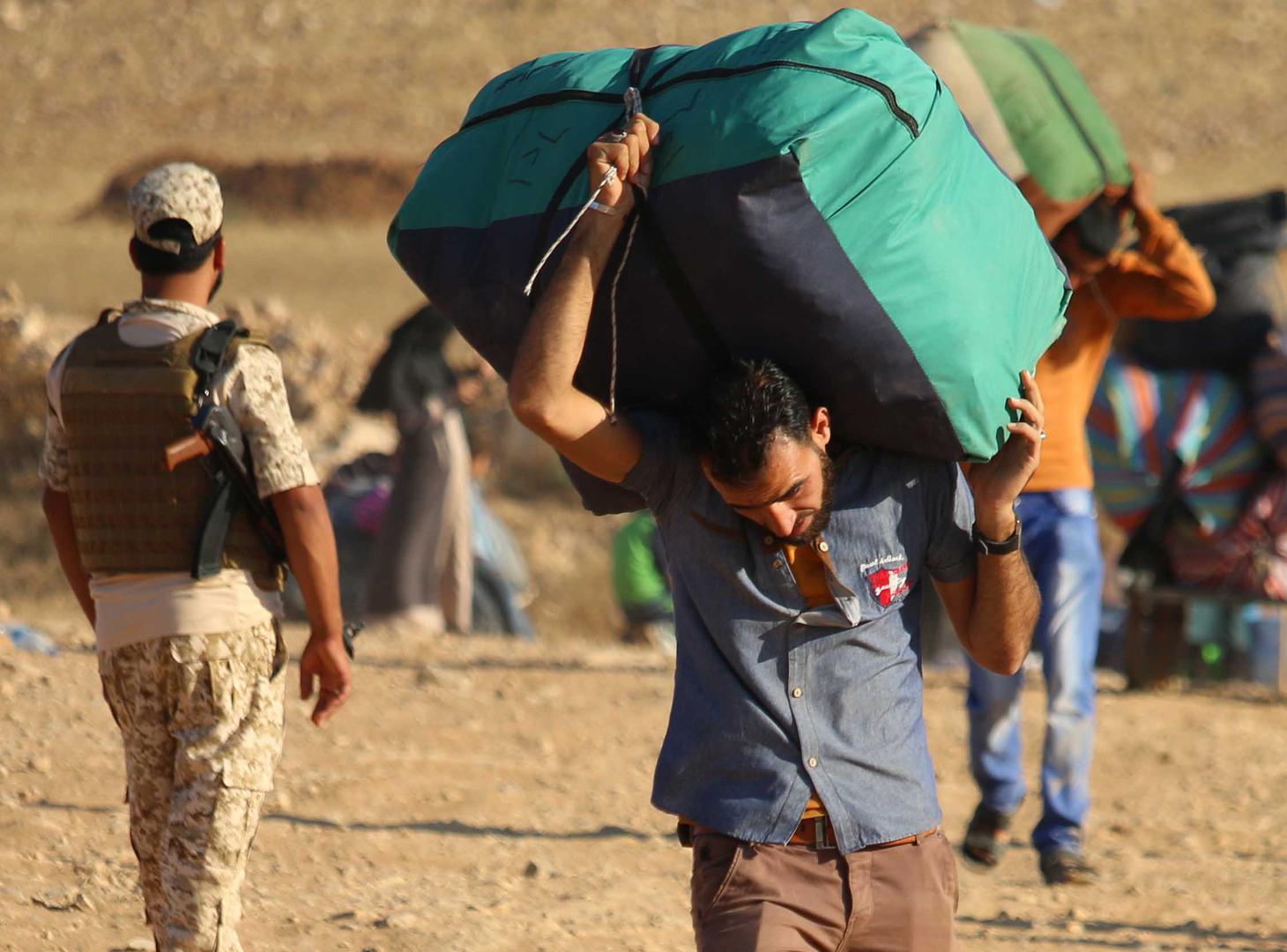 Syrian refugees carry belongings as they return to Syria after crossing the Jordanian border near the town of Nasib, in the southern province of Daraa, on August 29, 2017. 