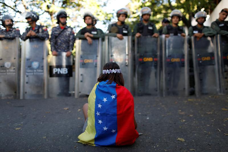 A girl wears a Venezuelan flag as Venezuelan security forces block access to opposition supporters and mourners of rogue ex-policeman Oscar Perez to the main morgue of the city, in Caracas, Venezuela January 20, 2018. 