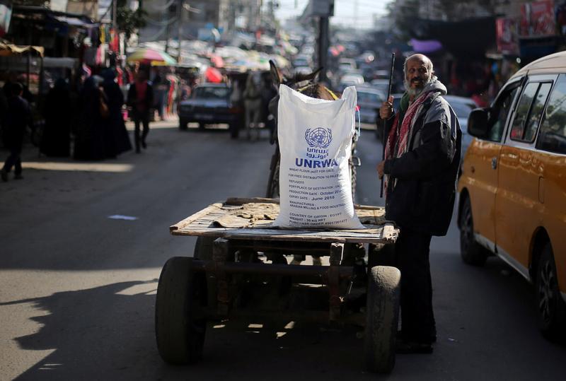 A Palestinian man stands next to a cart carrying a flour sack distributed by the United Nations Relief and Works Agency (UNRWA) in Khan Younis refugee camp in the southern Gaza Strip January 3, 2018. 