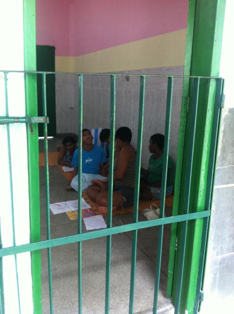 Crianças com deficiência física e sensorial desenham, sentadas no chão de um espaço comum em uma instituição no Rio de Janeiro. Desenhar é uma das poucas atividades que funcionários da instituição oferecem a crianças e adultos com deficiência. 