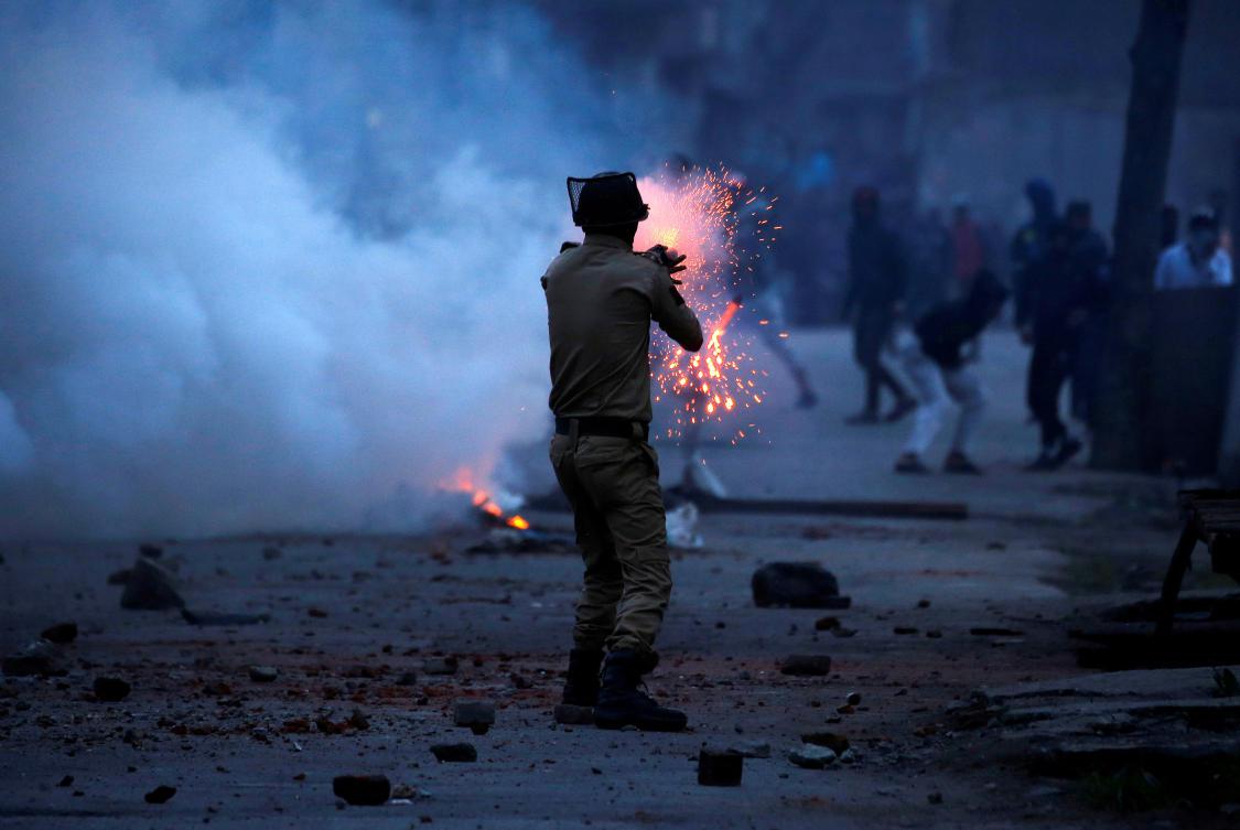 An Indian police officer fires a tear gas shell toward demonstrators, during a protest against the recent killings in Kashmir, in Srinagar, May 8, 2018.