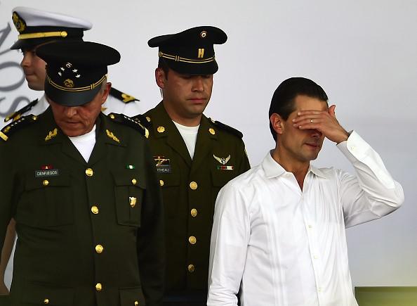 El presidente mexicano Enrique Peña Nieto (derecha) gesticula durante un evento conmemorativo del Día de la Bandera Mexicana en Iguala, estado de Guerreo, México, el 24 de febrero de 2016. 