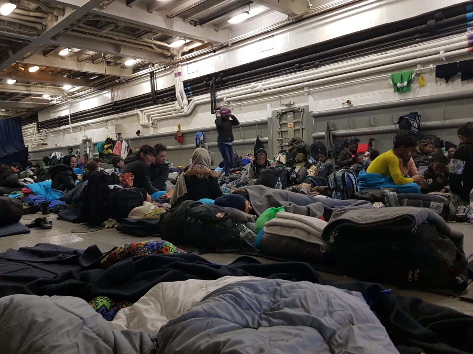 Women, men, and children inside the hull of a Greek Navy ship in Mytilene harbor, Lesbos, Greece. March 2020. © Private