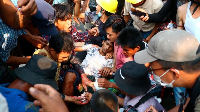 Protesters surround an injured man in Hlaing Tharyar township in Yangon, Myanmar, March 14, 2021.