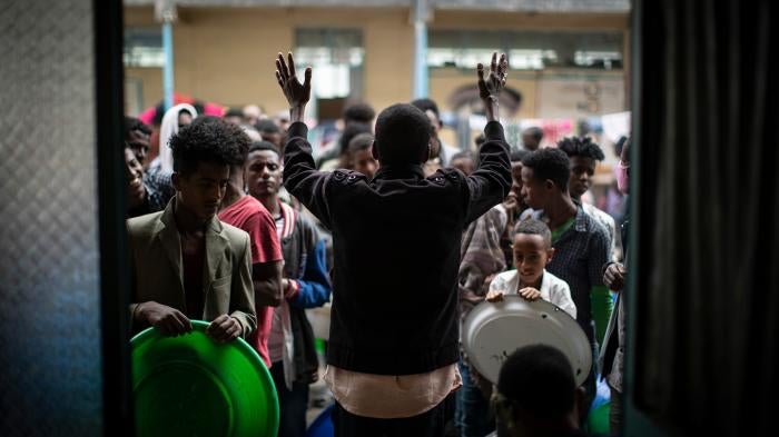 An organizer asks displaced Tigrayans to queue as they wait to receive food at a school in Mekele, in Ethiopia's northern Tigray region, May 5, 2021.