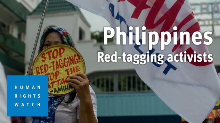 A woman holds up a sign protesting red-tagging in the Philippines 