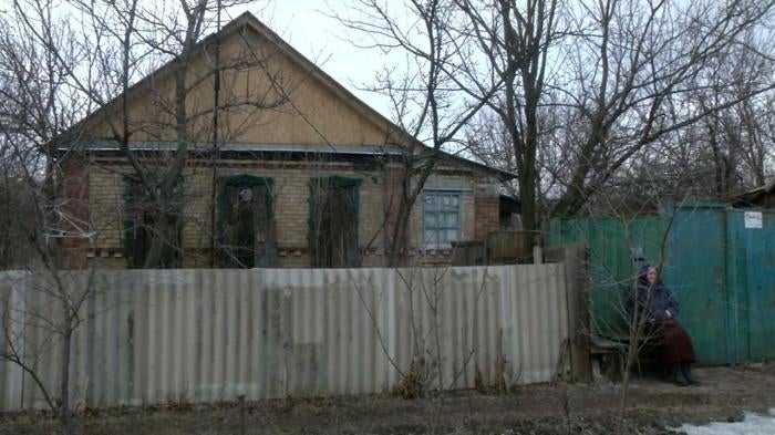 Older woman seating in font of a house in Ukraine
