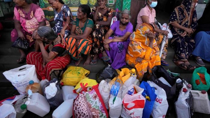 Women wait near an empty fuel station