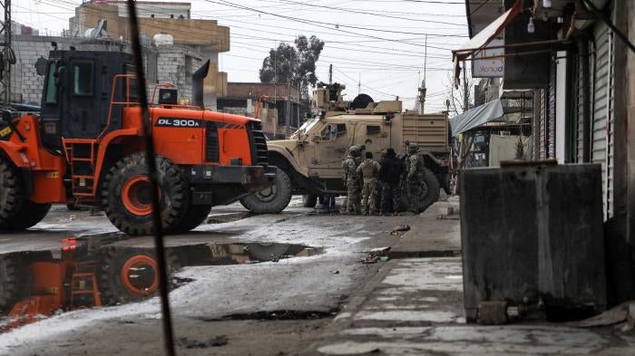 US soldiers and Syrian Democratic Forces standing by loader and military vehicles in East Ghweran neighbourhood at 2 p.m. on January 29, 2022.