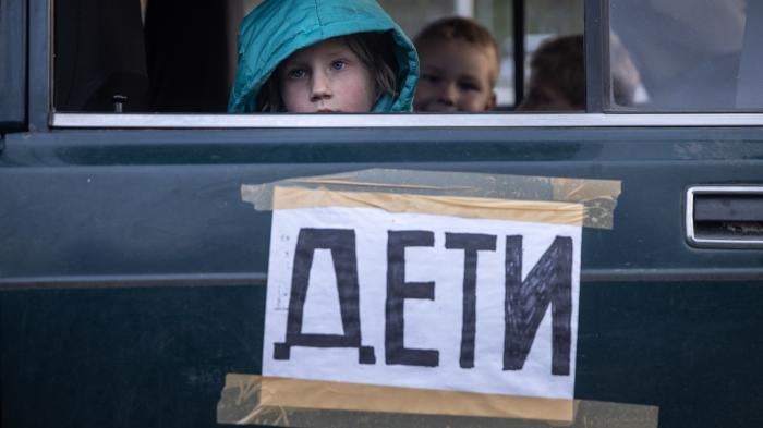 Children from Mariupol, Ukraine, look out the window of their family’s car, marked with the word “children,” after arriving at an evacuation point for people fleeing areas under Russian control.