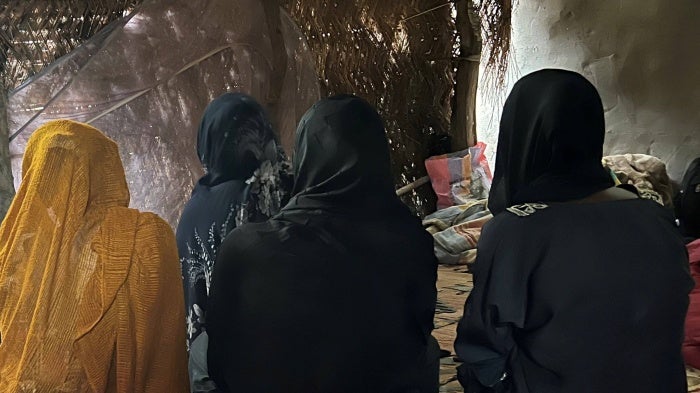 A group of women seated on the floor with their faces obscured 