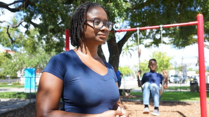 A woman stands in front of a boy on a swingset