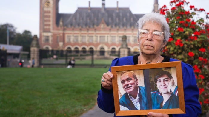 Fadwa Mahmoud holding photos of her husband and son who were detained in Syria in 2012 at the International Court of Justice in The Hague, Netherlands, on October 10, 2023.
