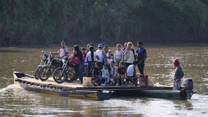 People cross a river to Venezuela from Tibu, Colombia on January 21, 2025, following fightings that killed dozens and forced thousands to flee their homes in the Colombian Catatumbo region.