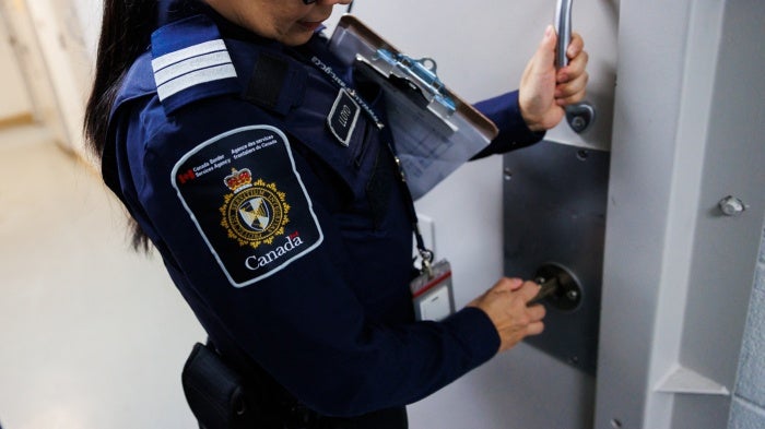 An officer demonstrates locking the door of a wet cell at the Toronto Immigration Holding Centre
