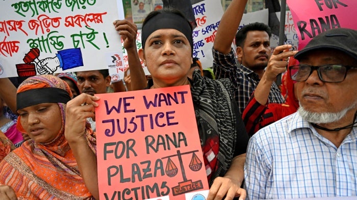 People hold protest signs that read "We want justice for Rana Plaza victims"
