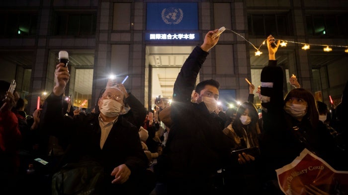 People protest outside a university building at night